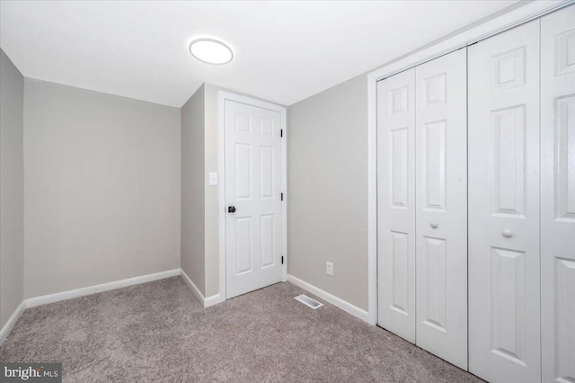 unfurnished bedroom with light colored carpet and a closet