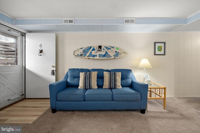 living room with wood-type flooring, a textured ceiling, and wood walls