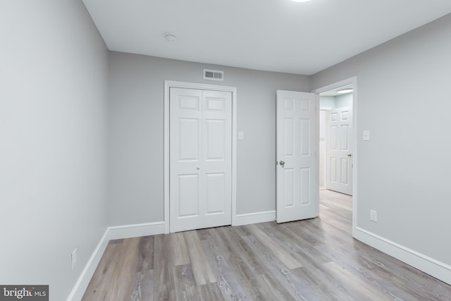 unfurnished bedroom with light wood-type flooring and a closet