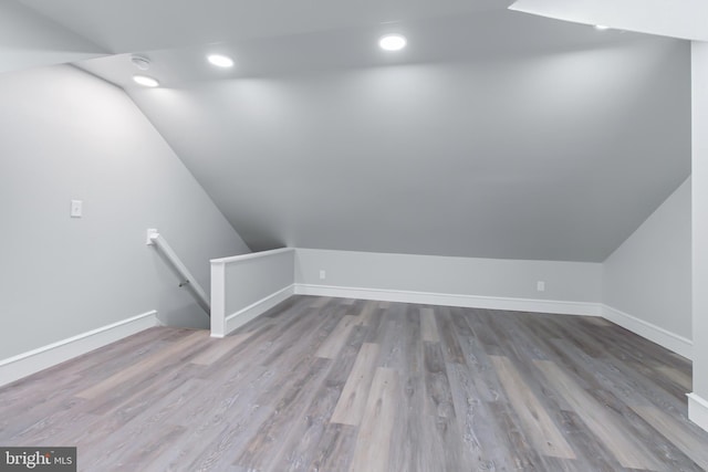 additional living space with hardwood / wood-style flooring and lofted ceiling