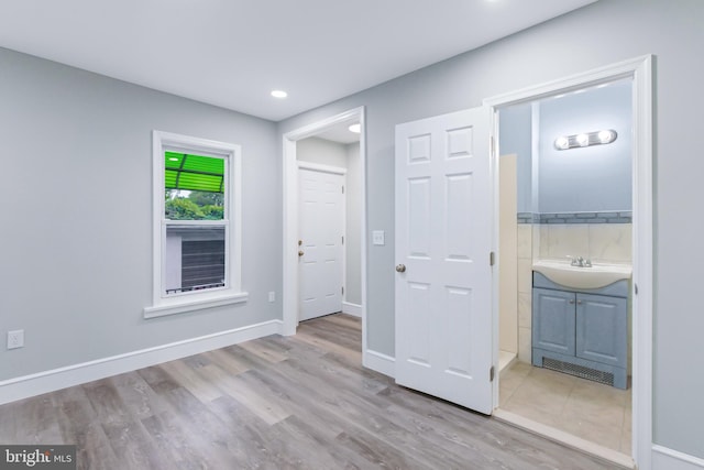 interior space with connected bathroom, light hardwood / wood-style flooring, and sink