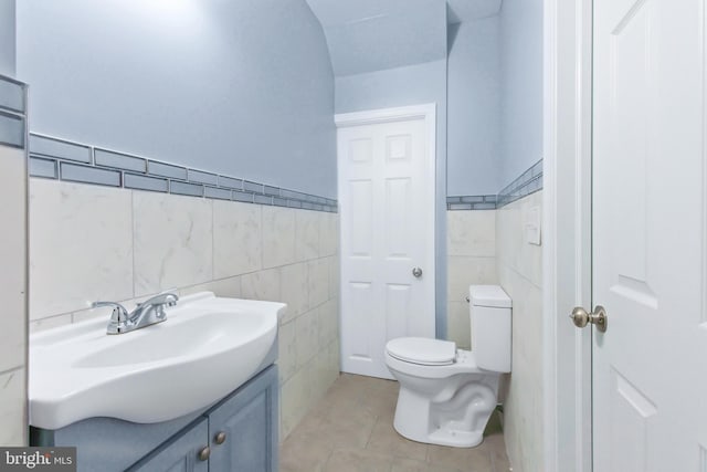 bathroom featuring tile patterned flooring, vanity, toilet, and tile walls