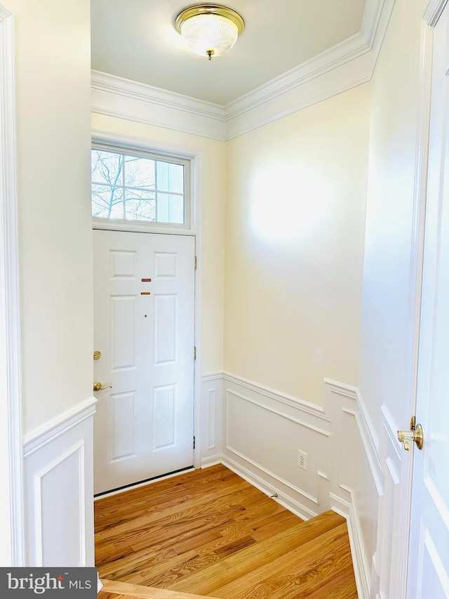 foyer entrance with light wood-type flooring and crown molding