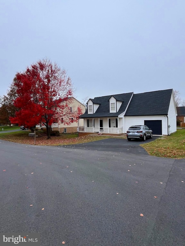 cape cod house featuring a porch and a garage