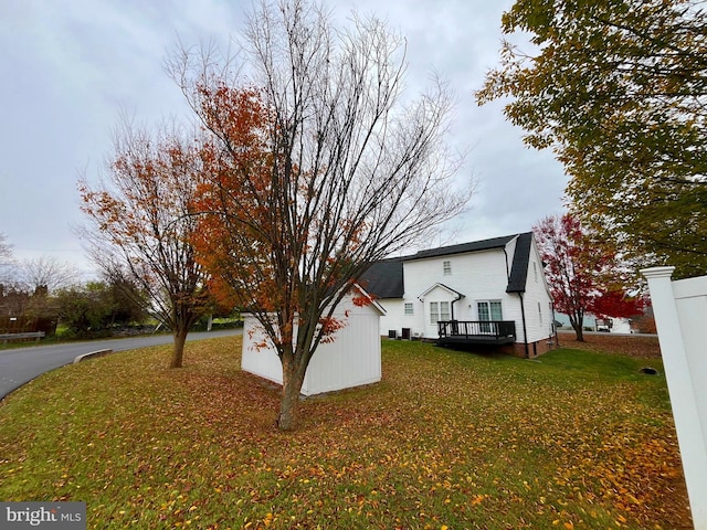 view of side of property featuring a storage unit, a wooden deck, and a lawn