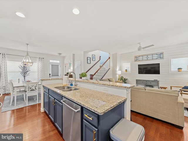 kitchen with stainless steel dishwasher, ceiling fan with notable chandelier, blue cabinetry, and hanging light fixtures