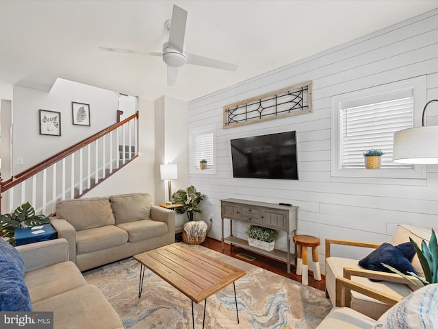 living room featuring hardwood / wood-style flooring, ceiling fan, and wood walls