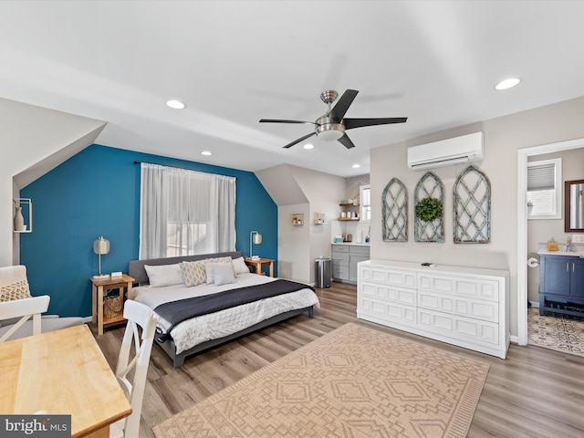 bedroom with a wall mounted AC, ceiling fan, and light wood-type flooring