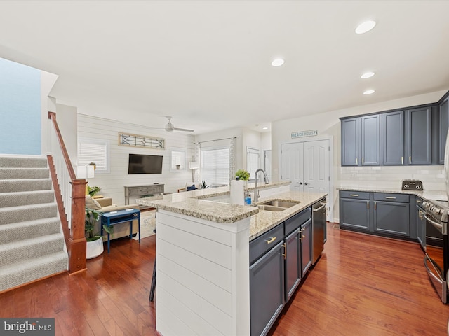 kitchen featuring a center island with sink, sink, ceiling fan, dark hardwood / wood-style floors, and light stone countertops