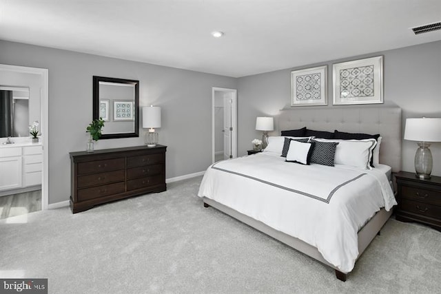 bedroom featuring ensuite bathroom and light carpet