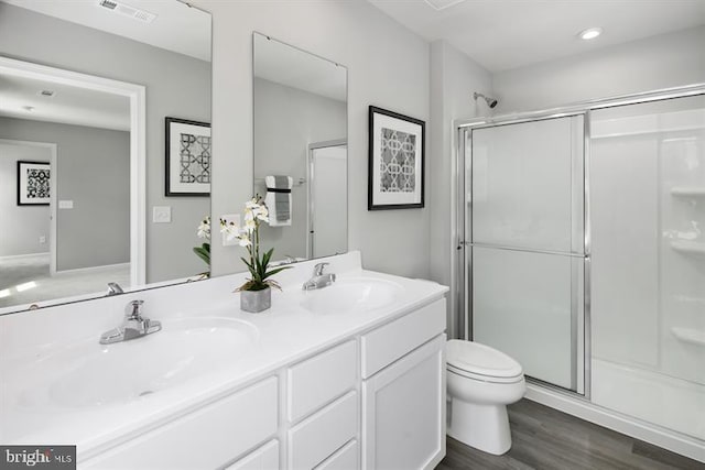 bathroom with vanity, toilet, wood-type flooring, and a shower with door