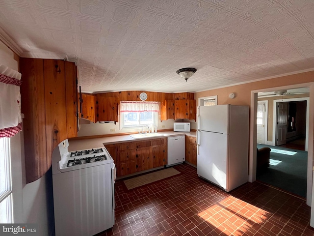 kitchen with white appliances, wooden walls, ornamental molding, and sink