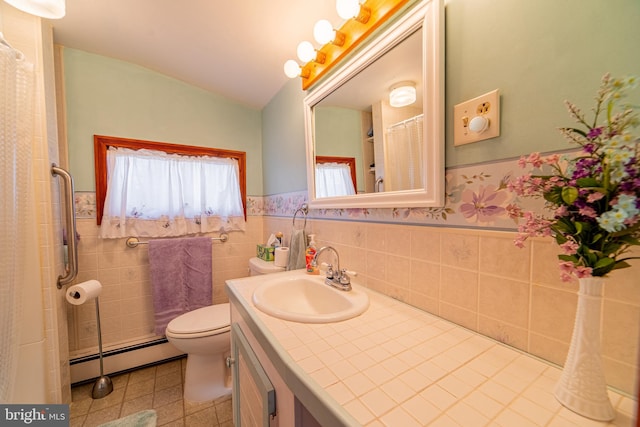 bathroom with vanity, toilet, baseboard heating, and tile walls