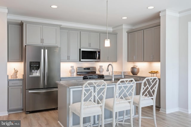 kitchen featuring gray cabinets, light stone counters, pendant lighting, and stainless steel appliances