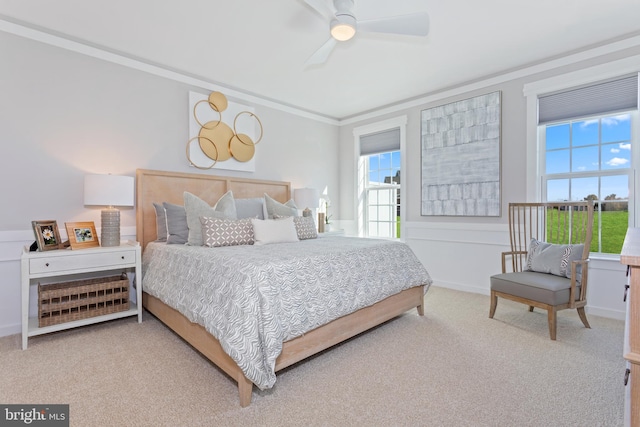 carpeted bedroom featuring ceiling fan and crown molding