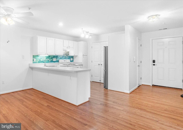 kitchen with sink, kitchen peninsula, white range with electric cooktop, light hardwood / wood-style floors, and white cabinets