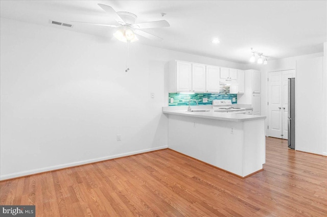 kitchen with white cabinets, decorative backsplash, white electric stove, kitchen peninsula, and light wood-type flooring