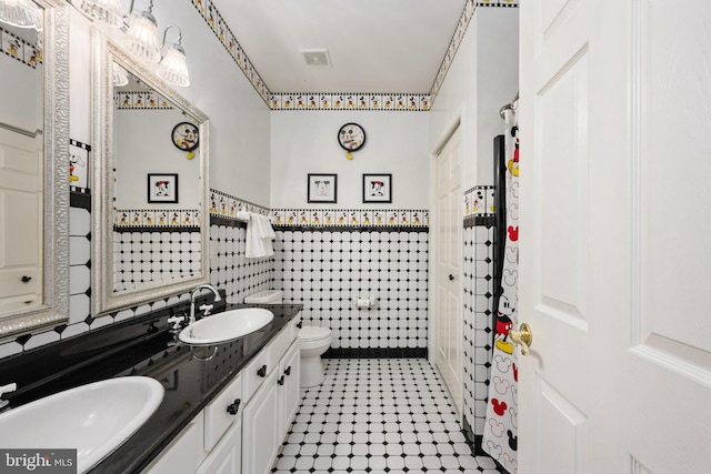 bathroom with vanity, toilet, and tile walls