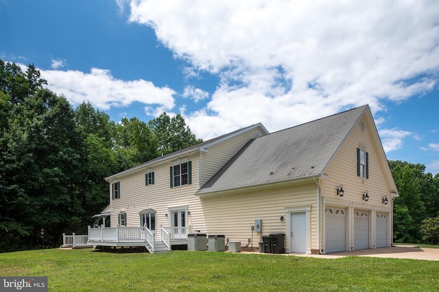 back of property with a lawn, central AC unit, a garage, and a deck