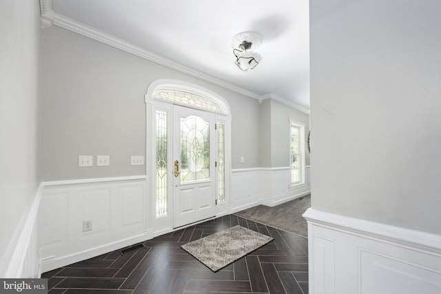 entryway with dark parquet flooring and crown molding