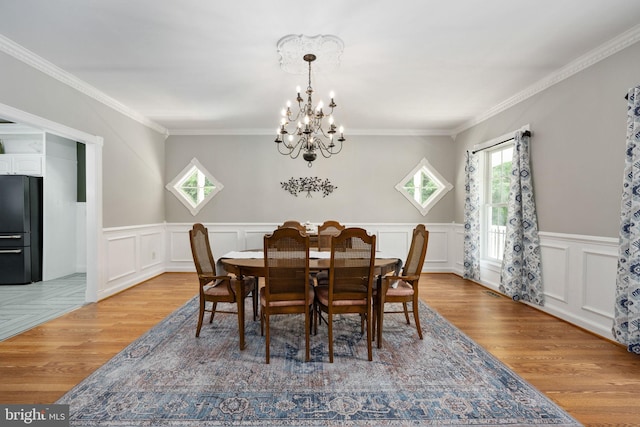 dining space featuring a notable chandelier, light hardwood / wood-style floors, and ornamental molding