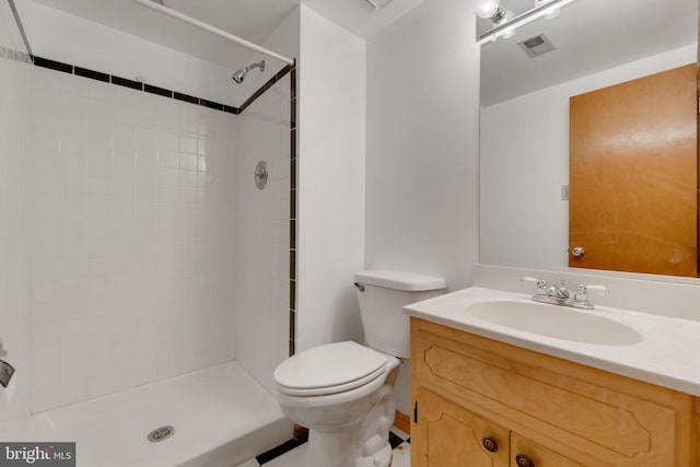 bathroom with vanity, toilet, and tiled shower