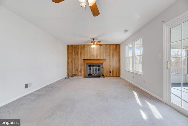 unfurnished living room with wooden walls, ceiling fan, and light colored carpet