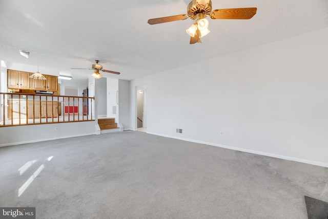 unfurnished living room featuring a textured ceiling, carpet floors, and ceiling fan