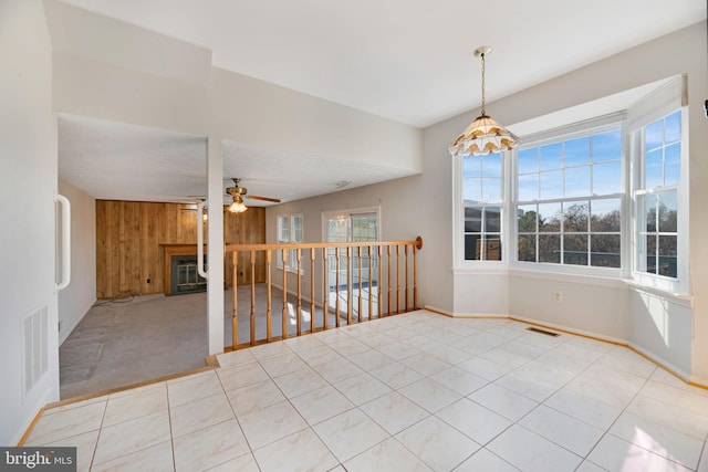 tiled spare room with ceiling fan, wood walls, and a wealth of natural light