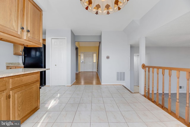 kitchen featuring black fridge and light tile patterned flooring