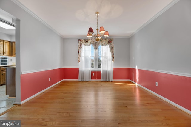 unfurnished dining area featuring light wood-type flooring, ornamental molding, and an inviting chandelier