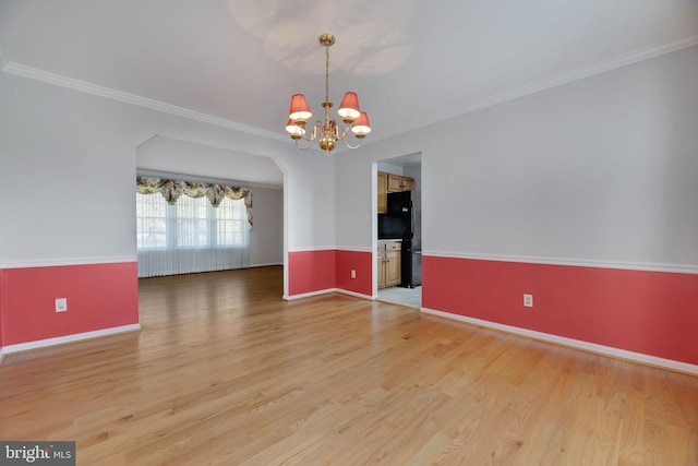 empty room with hardwood / wood-style flooring, ornamental molding, and a chandelier