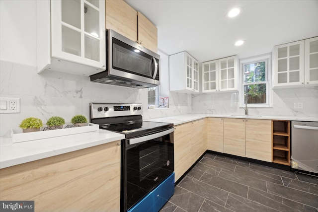 kitchen with light brown cabinetry, sink, appliances with stainless steel finishes, and tasteful backsplash