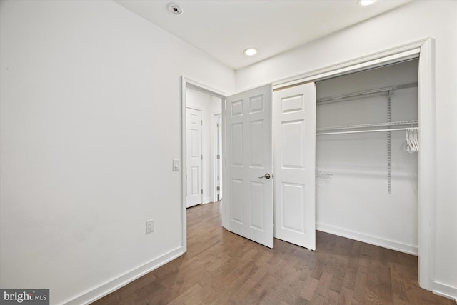 unfurnished bedroom with dark hardwood / wood-style flooring and a closet