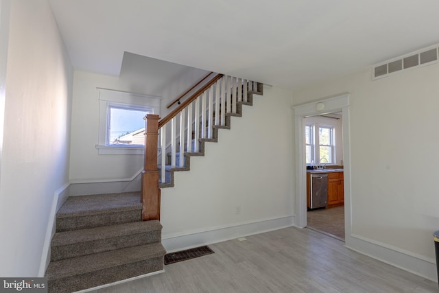 stairway with hardwood / wood-style floors, a healthy amount of sunlight, and sink