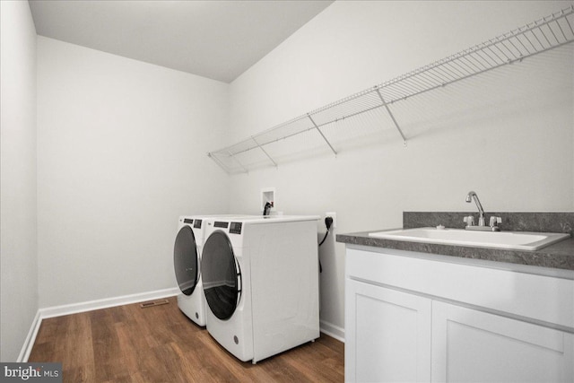 laundry area featuring dark hardwood / wood-style floors, cabinets, sink, and washing machine and clothes dryer