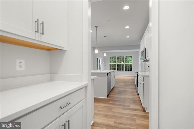 kitchen with white cabinets, pendant lighting, and stainless steel appliances