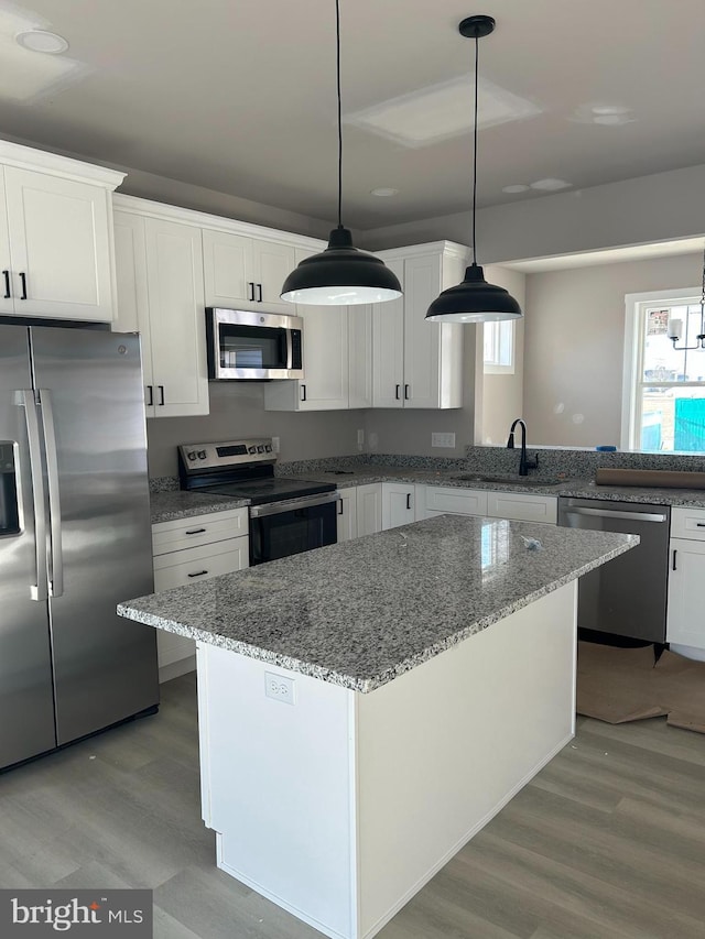 kitchen featuring sink, white cabinetry, light stone counters, hanging light fixtures, and stainless steel appliances