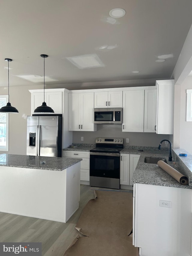 kitchen featuring appliances with stainless steel finishes, decorative light fixtures, white cabinetry, sink, and light stone countertops