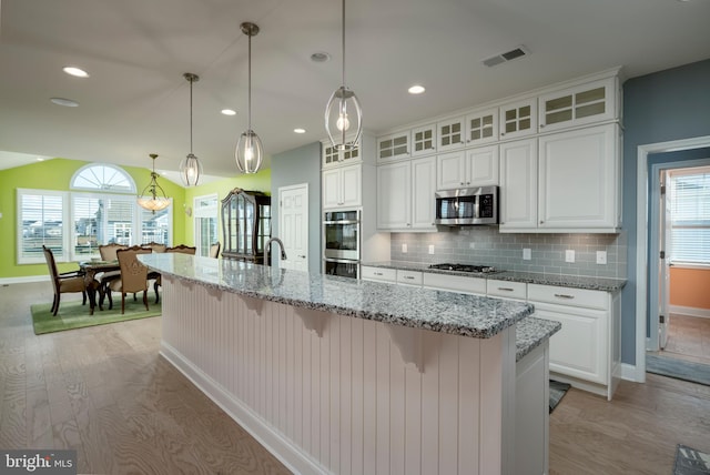 kitchen with a kitchen island with sink, white cabinetry, light hardwood / wood-style flooring, and stainless steel appliances