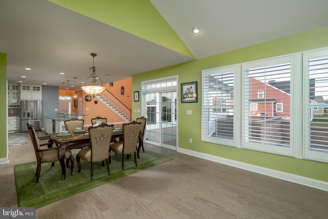 dining space with hardwood / wood-style flooring, vaulted ceiling, and sink