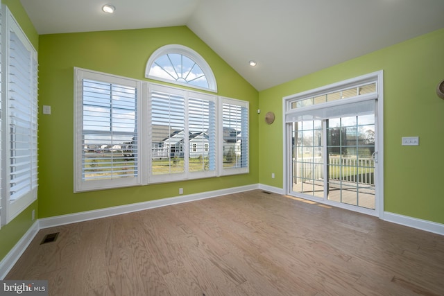 spare room with light hardwood / wood-style floors and vaulted ceiling