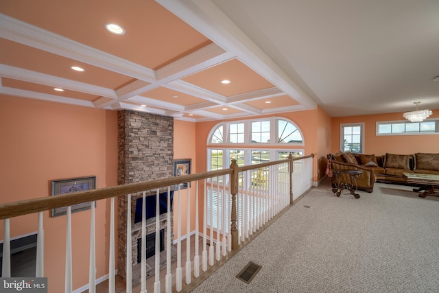 hallway with carpet flooring, beamed ceiling, coffered ceiling, and a notable chandelier