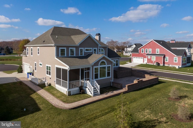 rear view of house featuring a sunroom, a yard, and a garage