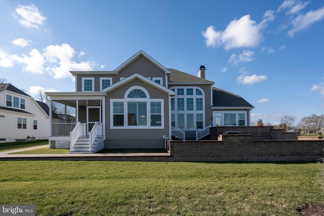 back of house featuring a lawn and a sunroom