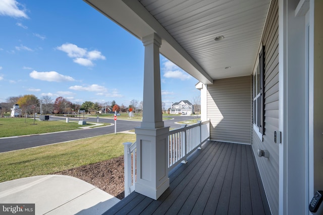 wooden deck featuring a porch and a lawn