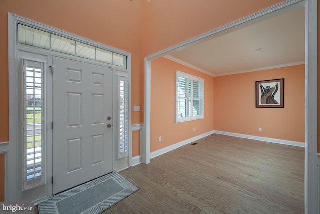 entryway with light hardwood / wood-style floors, a wealth of natural light, and ornamental molding