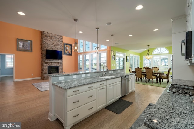 kitchen featuring sink, hanging light fixtures, light hardwood / wood-style floors, white cabinetry, and stainless steel appliances