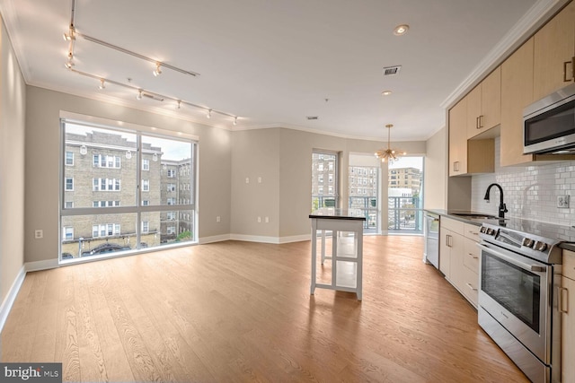 kitchen with decorative backsplash, hanging light fixtures, stainless steel appliances, and light wood-type flooring