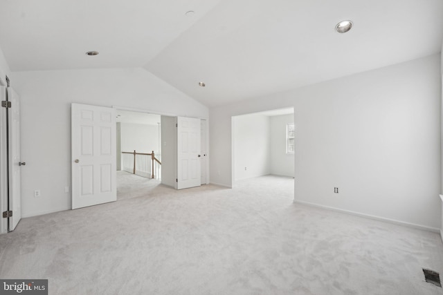 unfurnished bedroom with light colored carpet and lofted ceiling